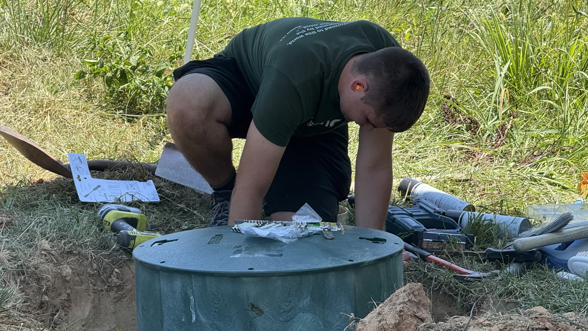 Technician securing a septic riser lid in a yard