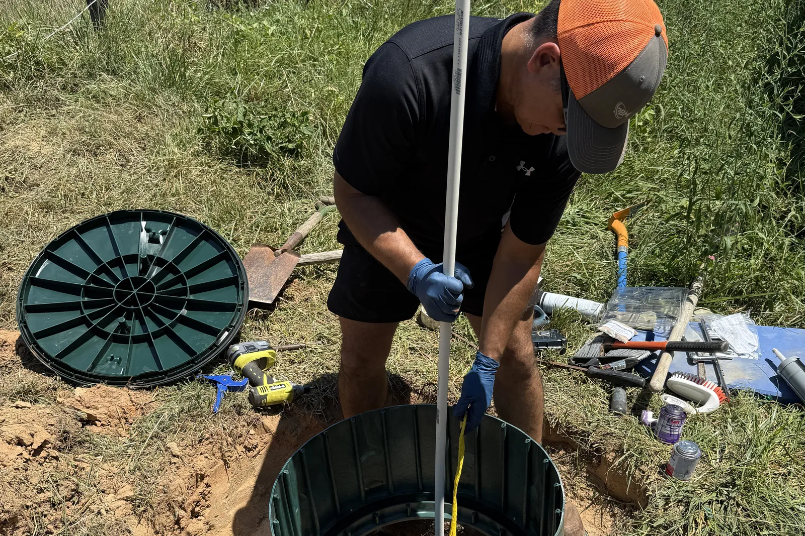 Technician guiding the air line down into a septic tank through the riser