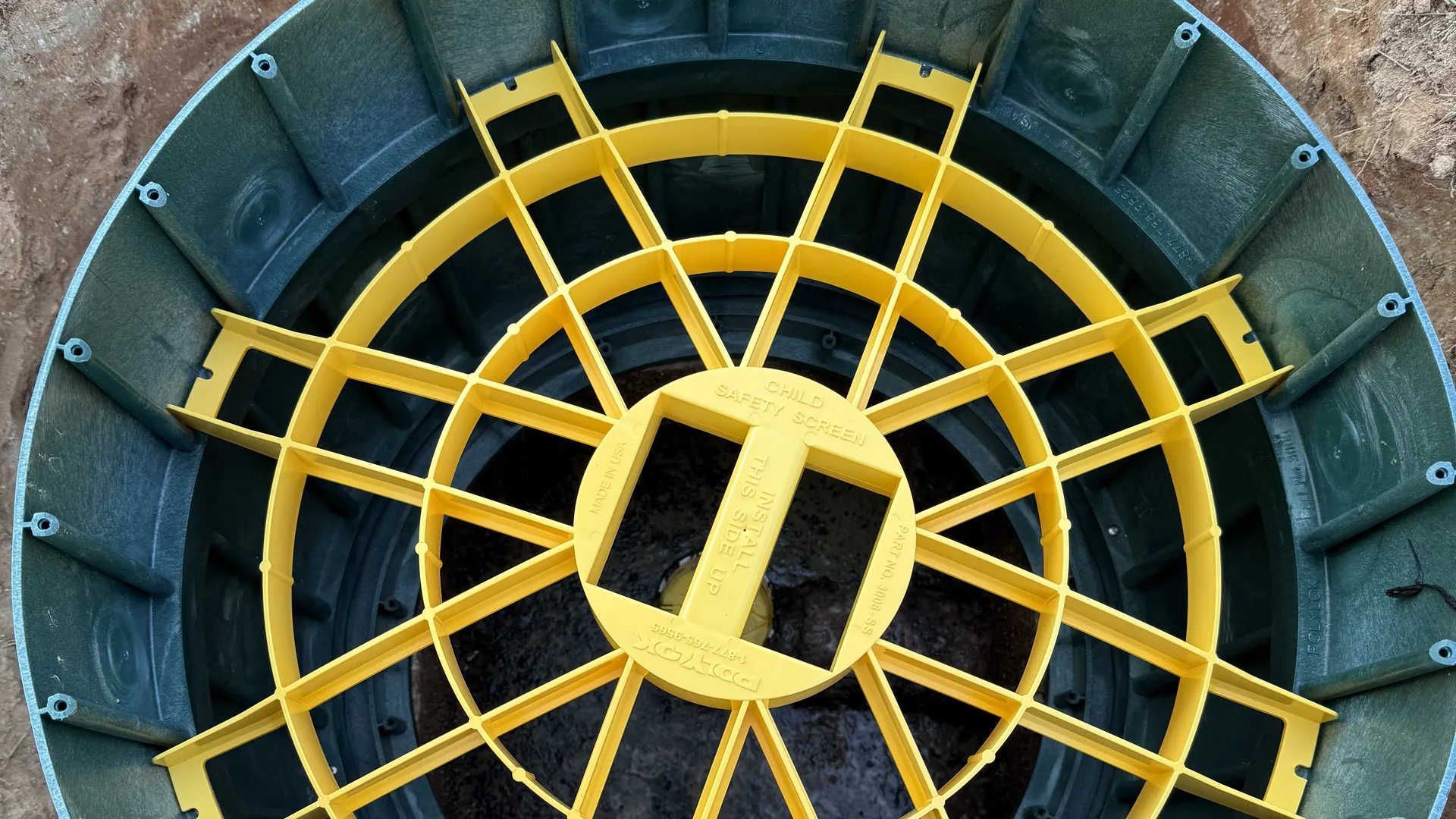 Overhead view of a septic riser with its yellow safety screen in place