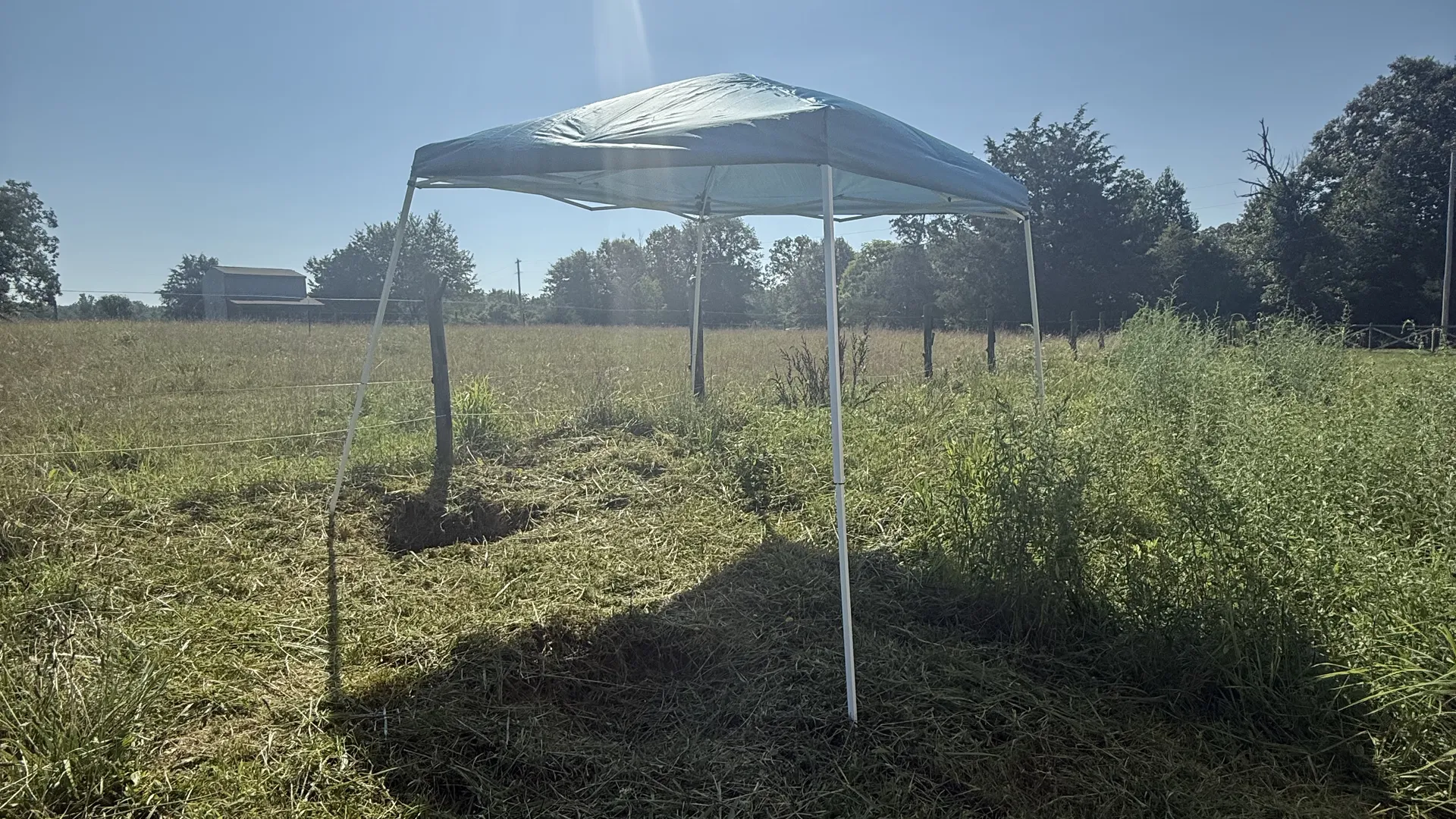 Work canopy set up in a mowed pasture on a septic service site