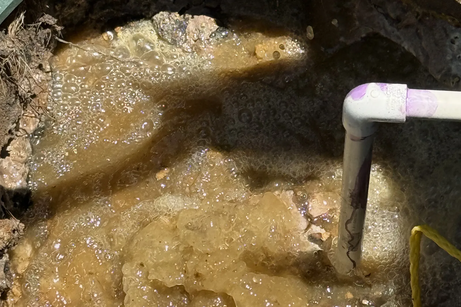 Foam and bubbles as aeration breaks up the crust inside a septic tank