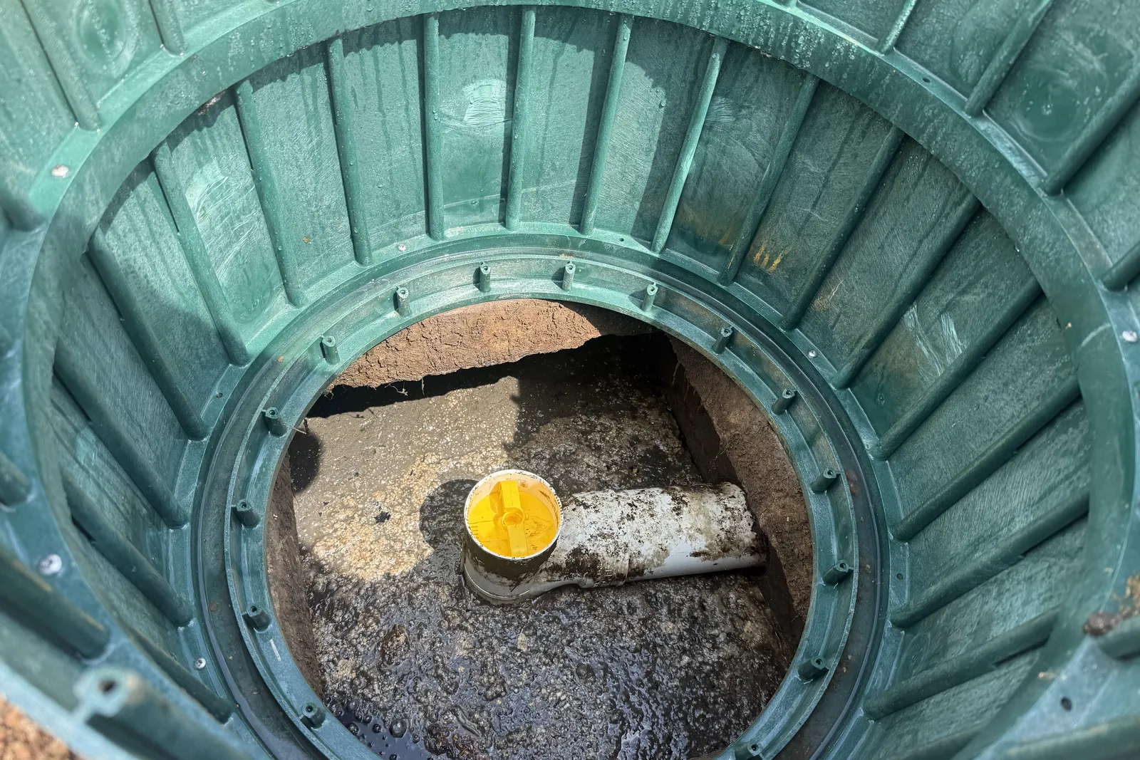 Looking into a septic tank through an open riser during an inspection