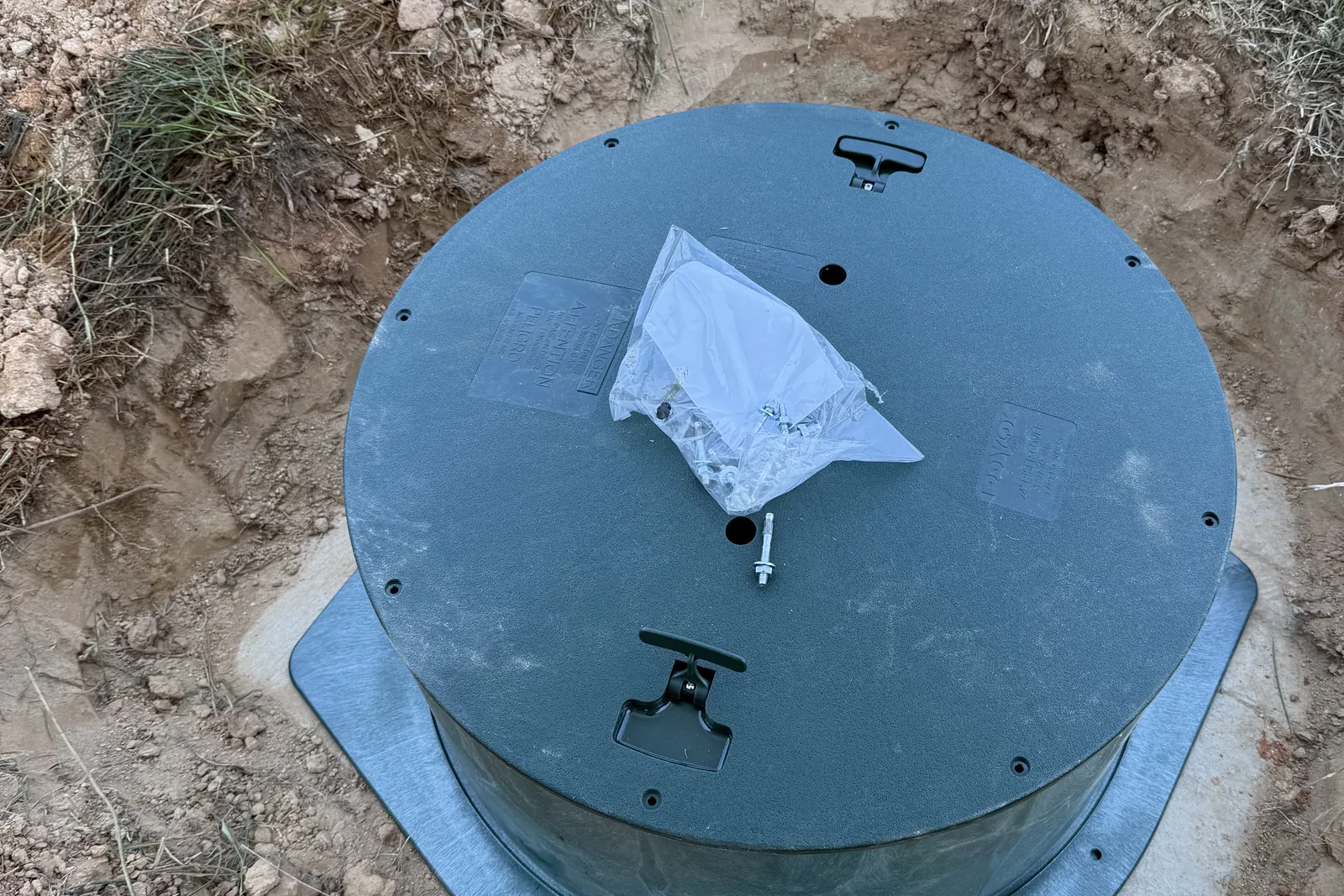 New green septic tank riser and lid installed on a concrete tank