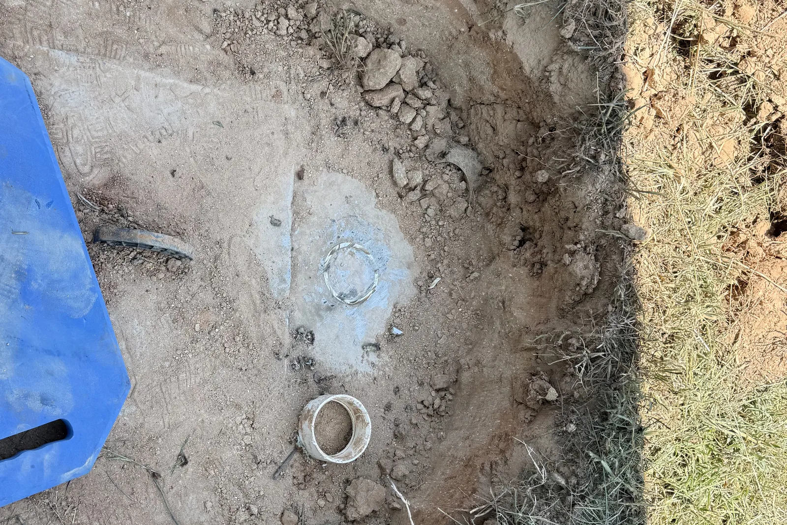 Small excavation exposing the top of a concrete septic tank